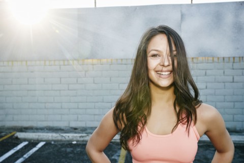 Sunbeams on smiling mixed race woman in parking lot