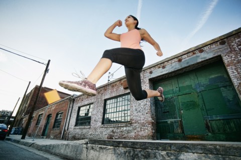 Mixed race woman jumping off loading dock