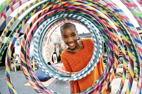 Portrait of smiling bald black woman behind hoops