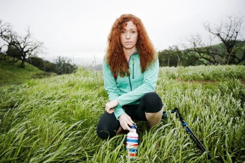 Portrait of crouching Caucasian woman holding bottle