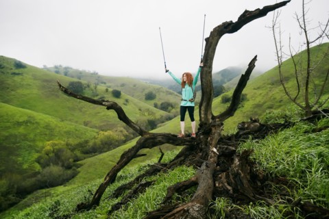 Caucasian woman standing on tree celebrating with walking sticks