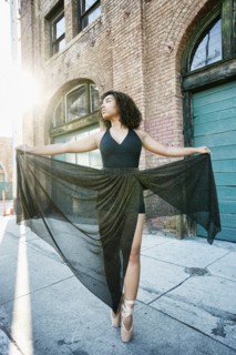 Sunbeams on mixed race woman dancing in city