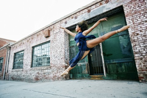 Mixed race woman dancing ballet in city