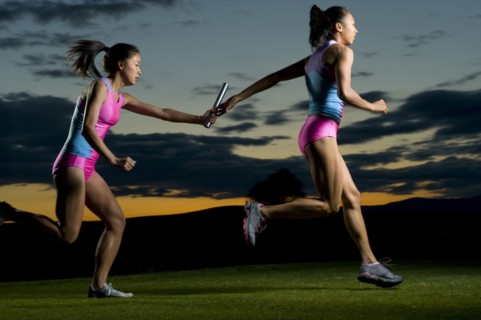 Relay runners passing baton in competition