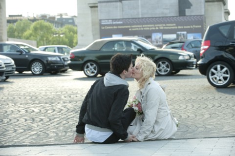 Caucasian man kissing girlfriend on busy street