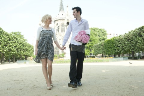 Caucasian couple holding hands in park near Notre Dame