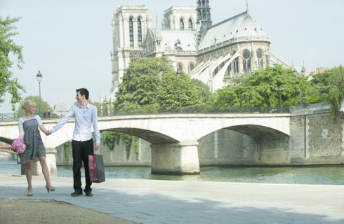 Caucasian couple walking along city river near Notre Dame