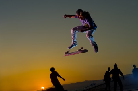 Skateboarder doing stunt in mid-air at sunset