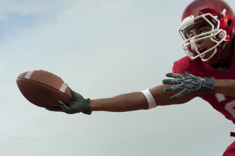 Black football player catching football