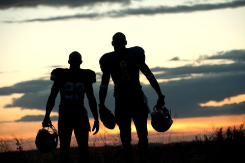 Silhouette of Black football players carrying helmet and football