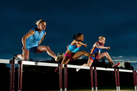 Runners jumping hurdles in race