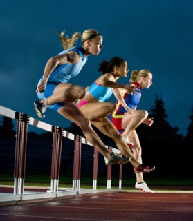 Runners jumping hurdles in race