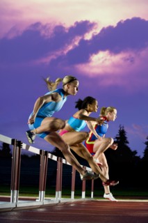 Runners jumping hurdles in race