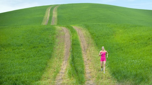 Caucasian woman running on path through field