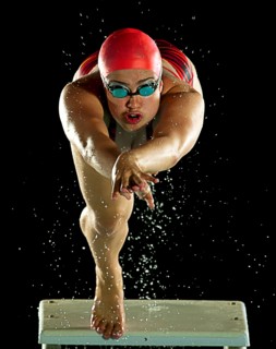 Mixed race swimmer diving off starting block