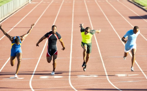 Runners running across finish line on track in race