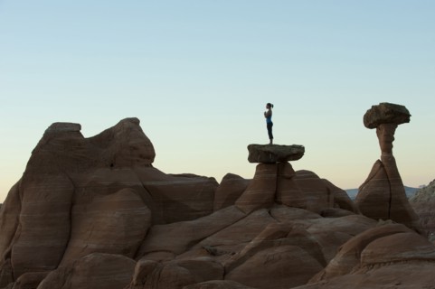 Caucasian woman practicing yoga on top of rock formation