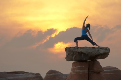 Caucasian woman practicing yoga on top of rock formation