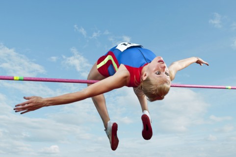 Caucasian athlete jumping over bar