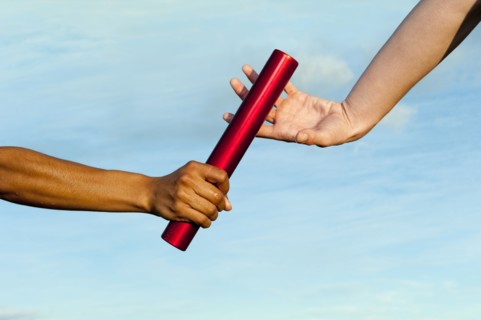 Runner passing baton to teammate