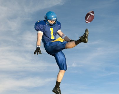 Caucasian football player kicking football