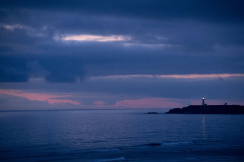 Lighthouse beaming from coastline at night