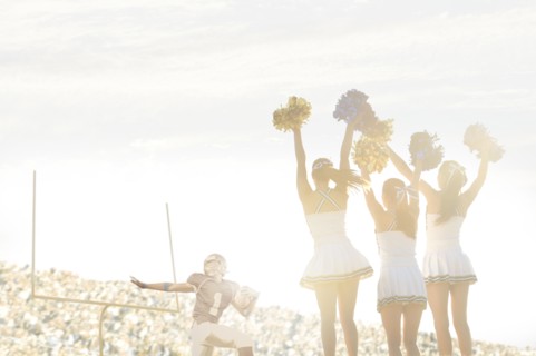 Caucasian cheerleaders on sidelines at football game