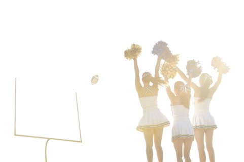 Caucasian cheerleaders on sidelines at football game
