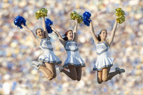 Caucasian cheerleaders jumping in mid-air