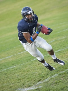 African American football player carrying ball