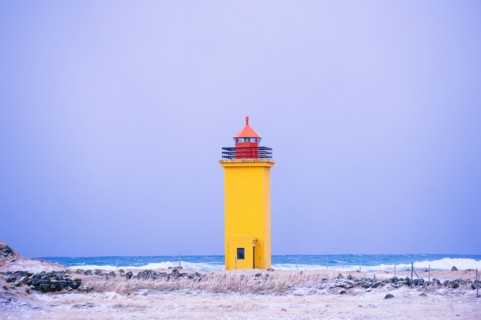 Yellow lighthouse on snowy coastline