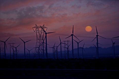Silhouette of wind turbines and power lines at sunset