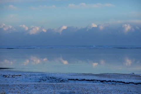 Clouds reflected in still ocean in arctic landscape