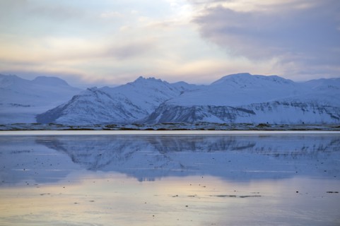 Mountains reflected in still ocean in arctic landscape