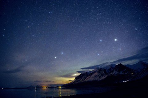 Starry sky over still ocean in arctic landscape