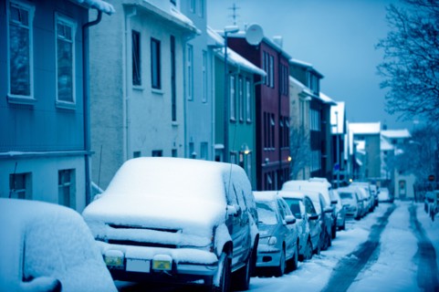 Snow covered cars parked on city street