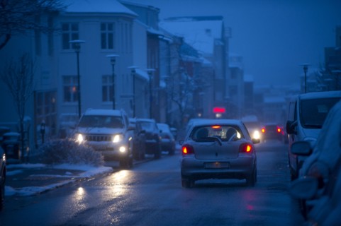 Cars driving on snowy city street at night