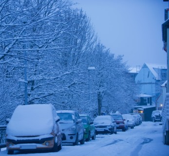 Snow covered cars parked on city street