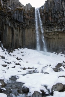 Waterfall and steep cliff in snowy landscape