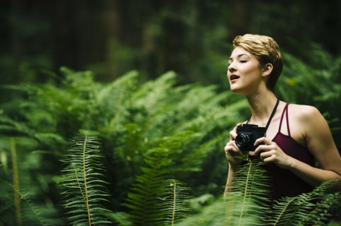 Caucasian woman holding camera in forest