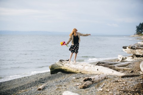 Girl balancing on driftwood on beach