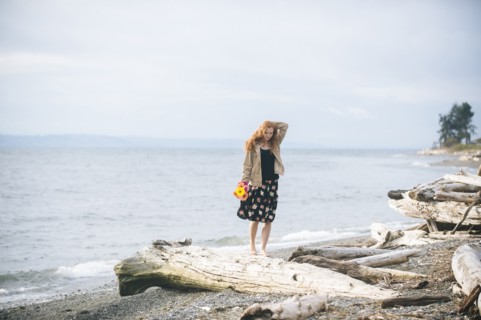Girl standing on driftwood on beach