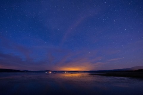Still rural lake under starry night sky
