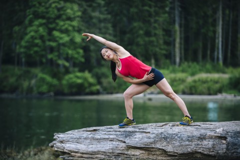 Korean runner stretching on rock near lake