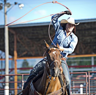 Caucasian cowgirl on horse throwing lasso in rodeo on ranch