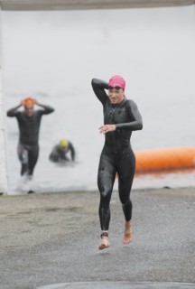 Athlete in triathlon removing wet suit after swimming