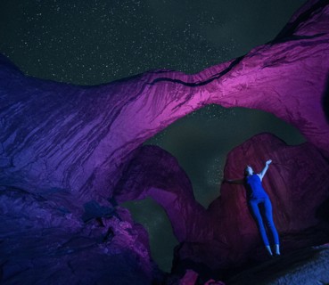 Woman standing in illuminated rocks at night in Arches National Park