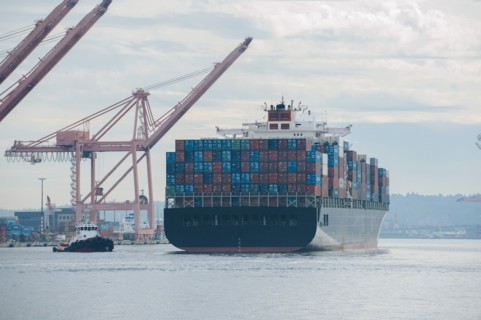Tugboat and container ship in industrial harbor