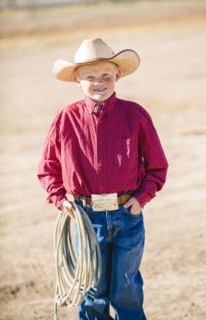 Caucasian boy in cowboy outfit carrying lasso