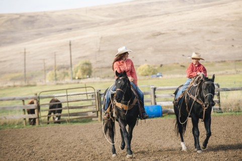 Caucasian mother and son riding horses on ranch